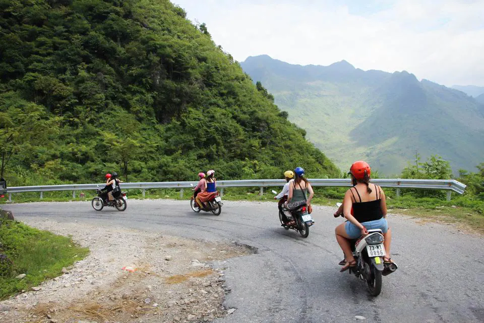 A small group riding the Ha Giang Loop road between two mountain passes